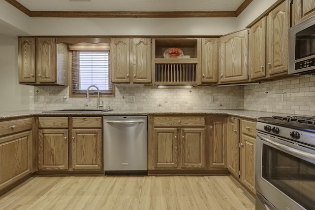 kitchen with ornamental molding, appliances with stainless steel finishes, sink, and light wood-type flooring