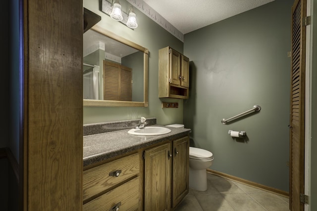 bathroom featuring tile patterned flooring, vanity, a textured ceiling, and toilet