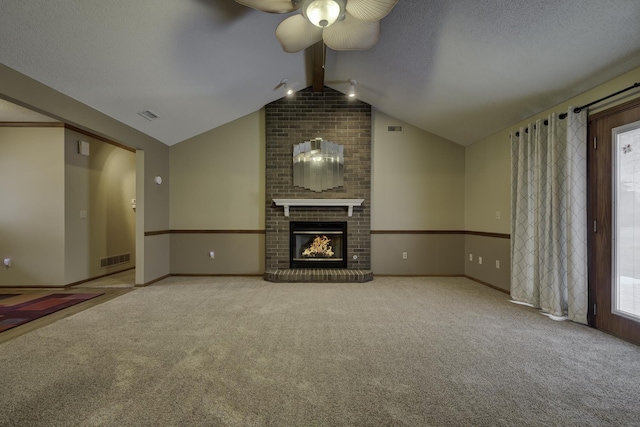 unfurnished living room with lofted ceiling with beams, carpet floors, a brick fireplace, and a textured ceiling