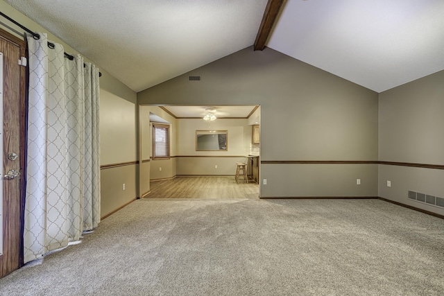 unfurnished living room with light carpet and vaulted ceiling with beams