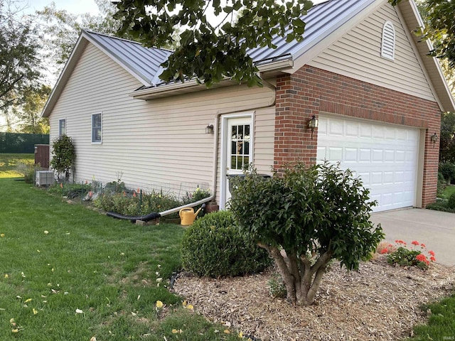 view of side of home with a garage, central AC, and a lawn