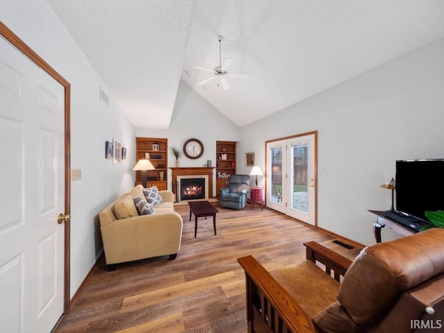 living room with ceiling fan, high vaulted ceiling, hardwood / wood-style floors, and a textured ceiling