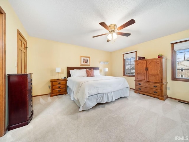 bedroom with multiple windows, a textured ceiling, light carpet, and ceiling fan