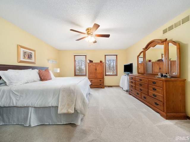 bedroom featuring ceiling fan, light colored carpet, and a textured ceiling