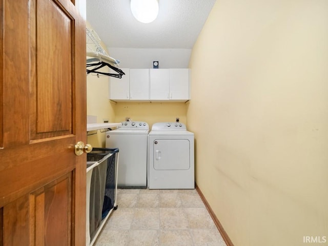 laundry room featuring cabinets, washing machine and clothes dryer, and a textured ceiling