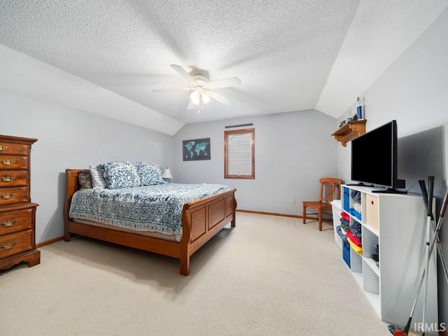 bedroom featuring ceiling fan, vaulted ceiling, light colored carpet, and a textured ceiling