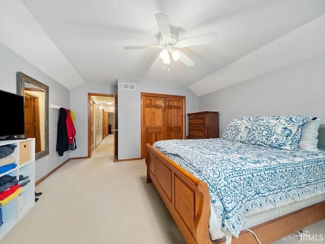 bedroom featuring lofted ceiling, light carpet, a textured ceiling, and a closet