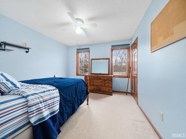 bedroom with ceiling fan, light colored carpet, and a textured ceiling