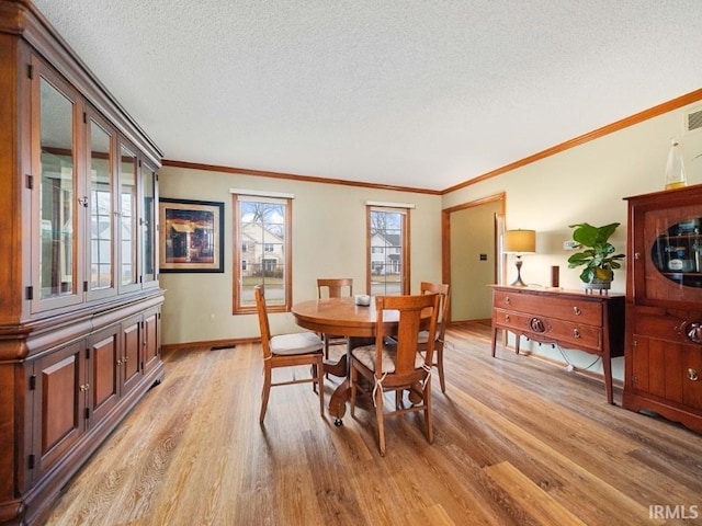 dining space featuring ornamental molding, a textured ceiling, and light wood-type flooring