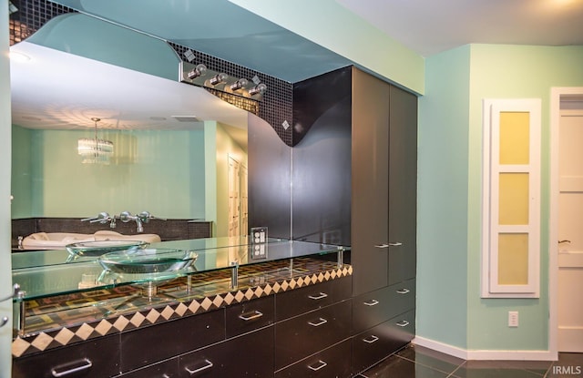 walk in closet with dark tile patterned floors and an inviting chandelier