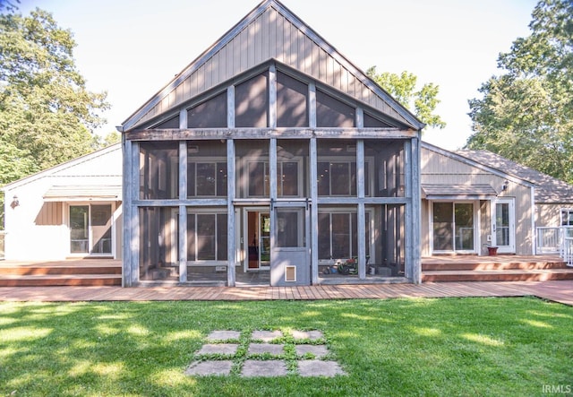 back of property with a wooden deck, a lawn, and a sunroom