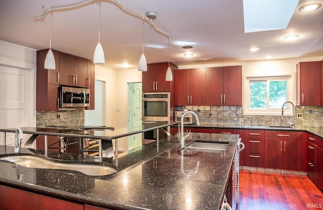 kitchen featuring appliances with stainless steel finishes, sink, hanging light fixtures, and dark stone counters