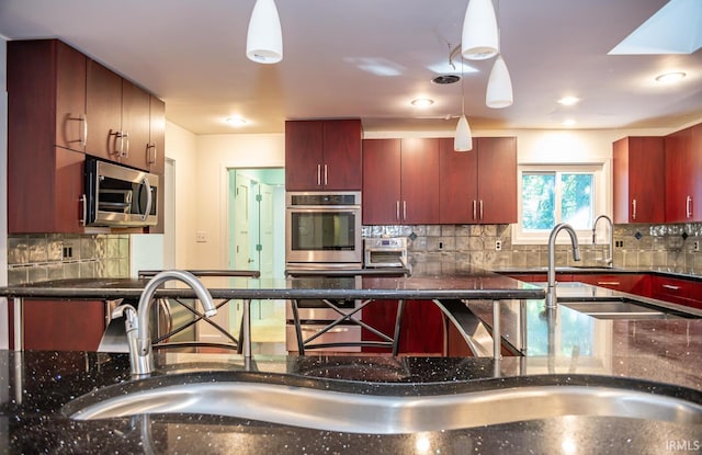 kitchen featuring hanging light fixtures, appliances with stainless steel finishes, sink, and decorative backsplash