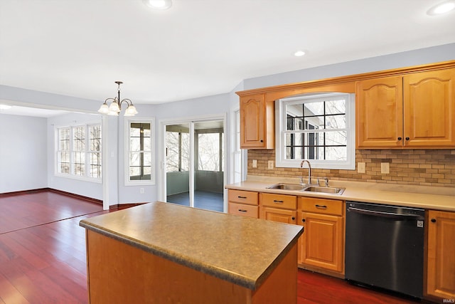 kitchen featuring dark wood-type flooring, sink, hanging light fixtures, dishwasher, and a kitchen island