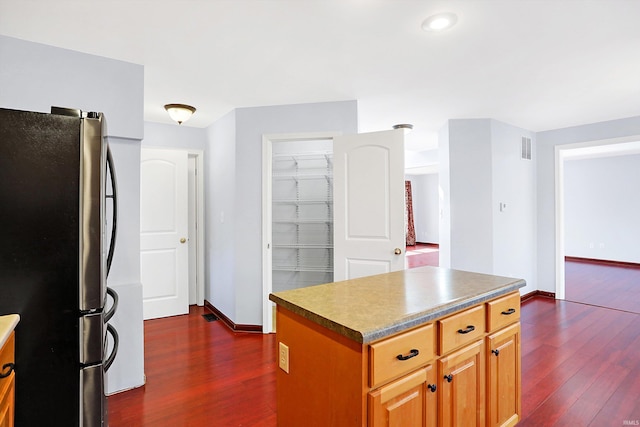 kitchen featuring a center island, dark wood-type flooring, and stainless steel refrigerator