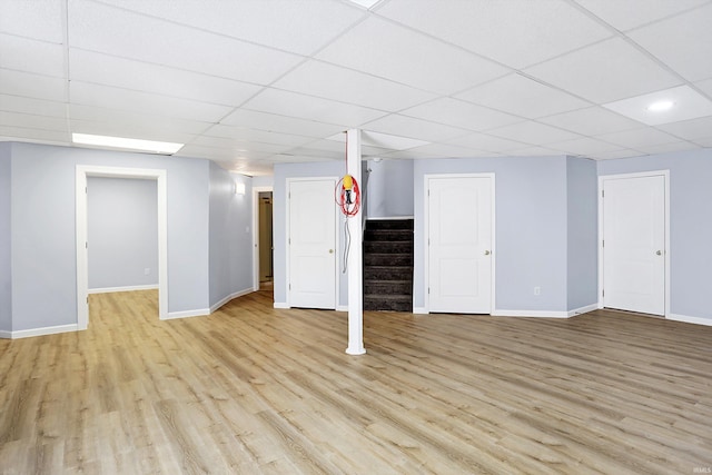 basement with a paneled ceiling and light wood-type flooring