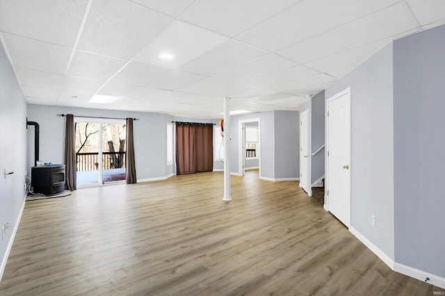 interior space featuring a paneled ceiling, a wood stove, and light wood-type flooring