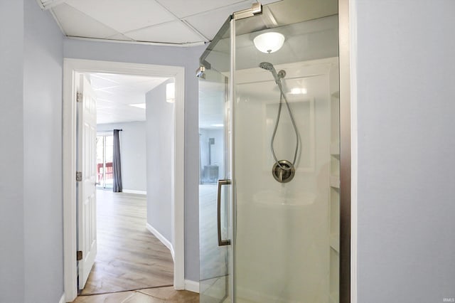 bathroom with a paneled ceiling, wood-type flooring, and walk in shower