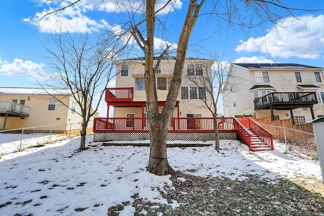 snow covered back of property with a deck