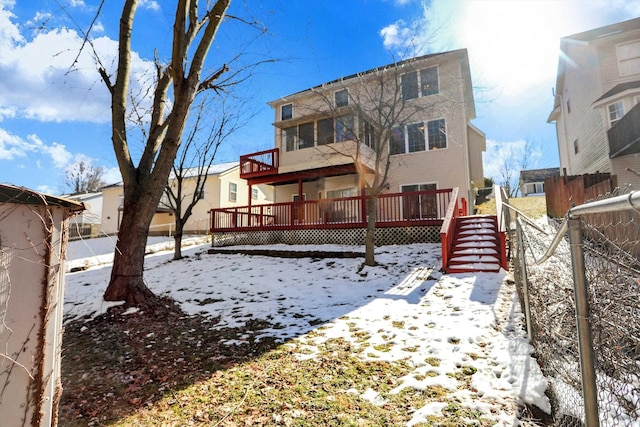 snow covered back of property with a wooden deck