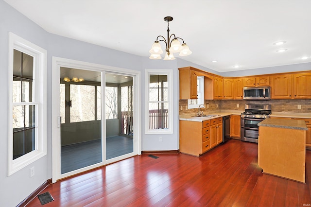 kitchen with pendant lighting, sink, tasteful backsplash, and appliances with stainless steel finishes