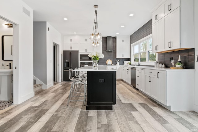 kitchen featuring a breakfast bar, a center island, appliances with stainless steel finishes, pendant lighting, and white cabinets