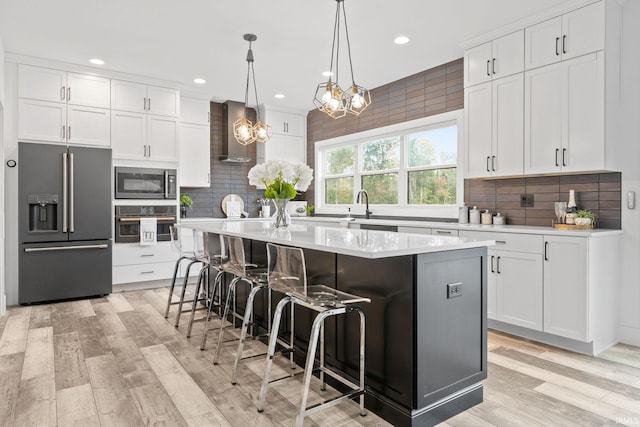 kitchen with white cabinetry, stainless steel appliances, a kitchen breakfast bar, and an island with sink