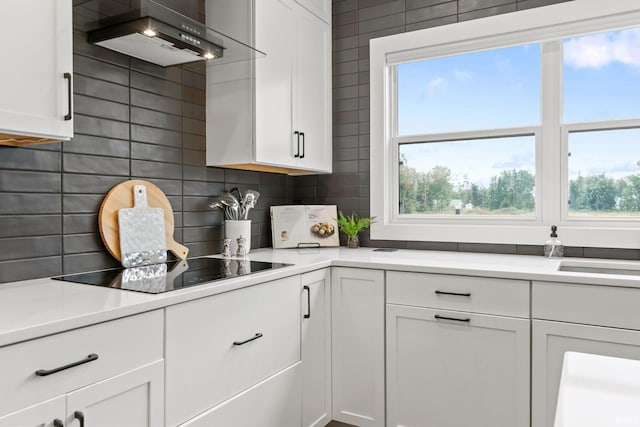 kitchen featuring tasteful backsplash, plenty of natural light, white cabinets, and wall chimney exhaust hood