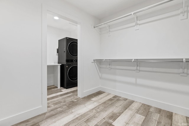 walk in closet with stacked washer / drying machine and light hardwood / wood-style flooring