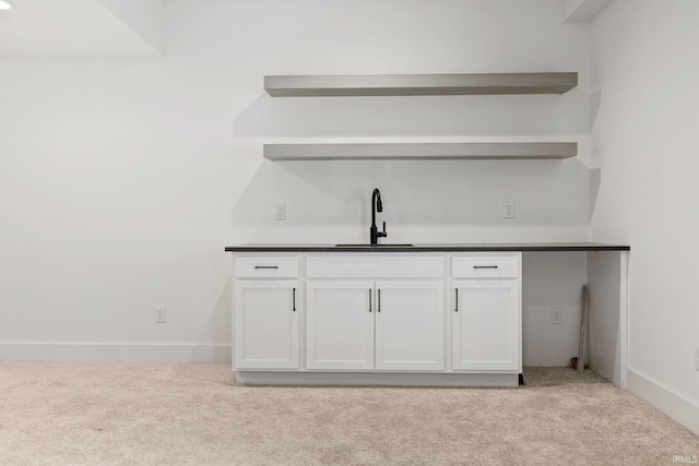 bar featuring white cabinetry, sink, and light carpet