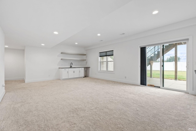 unfurnished living room with light carpet and sink