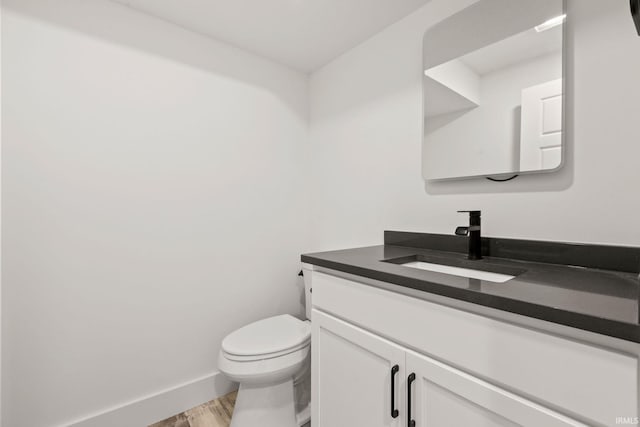 bathroom with hardwood / wood-style flooring, vanity, and toilet