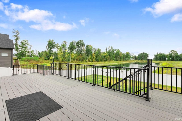 wooden terrace featuring a water view and a lawn