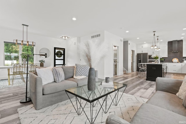 living room with an inviting chandelier and light hardwood / wood-style flooring