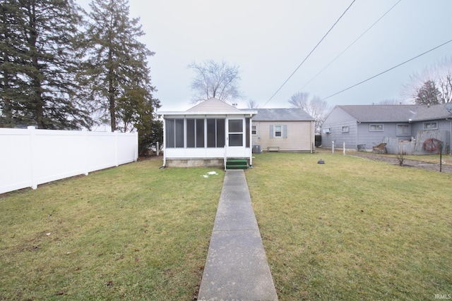 rear view of house featuring a sunroom and a lawn