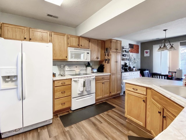 kitchen featuring hanging light fixtures, sink, white appliances, and light hardwood / wood-style floors