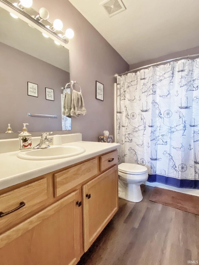 bathroom with hardwood / wood-style flooring, vanity, curtained shower, and toilet