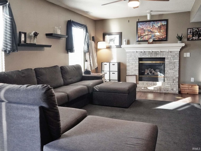 living room featuring ceiling fan, hardwood / wood-style floors, and a fireplace