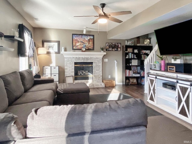 living room with hardwood / wood-style flooring, ceiling fan, and a brick fireplace