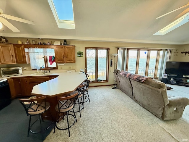 kitchen with a healthy amount of sunlight, vaulted ceiling with skylight, sink, and a breakfast bar area