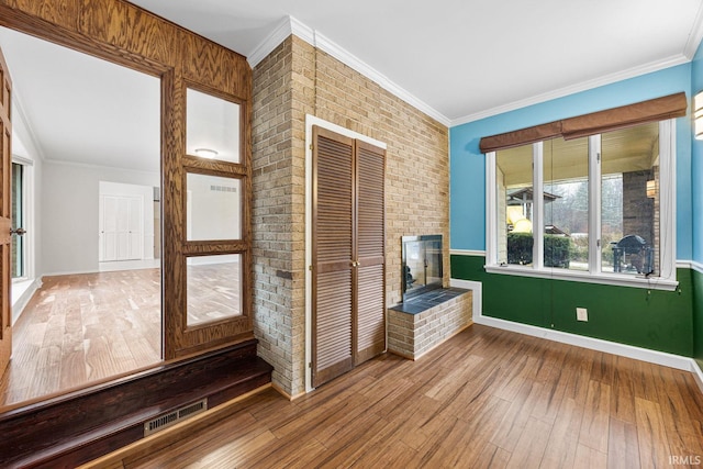 interior space with hardwood / wood-style flooring, ornamental molding, and a fireplace