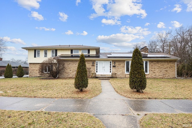 view of front of home with a front lawn and solar panels