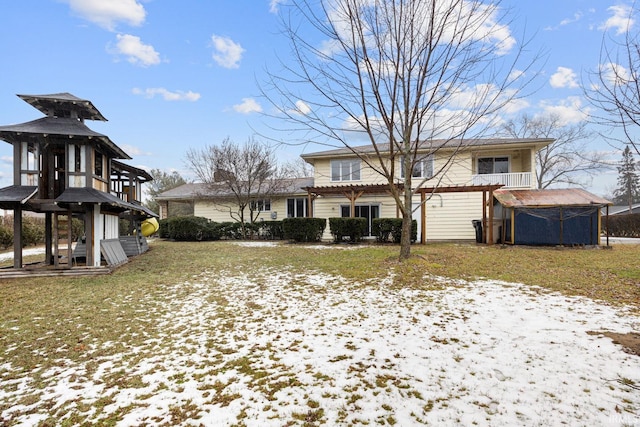 snow covered house featuring a pergola and a lawn