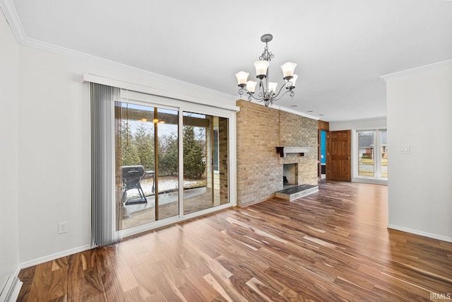 unfurnished living room featuring a large fireplace, ornamental molding, a chandelier, and hardwood / wood-style floors