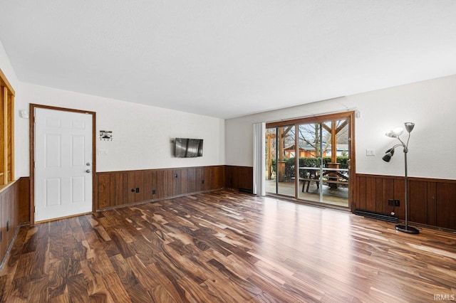 unfurnished living room with dark hardwood / wood-style floors and wooden walls