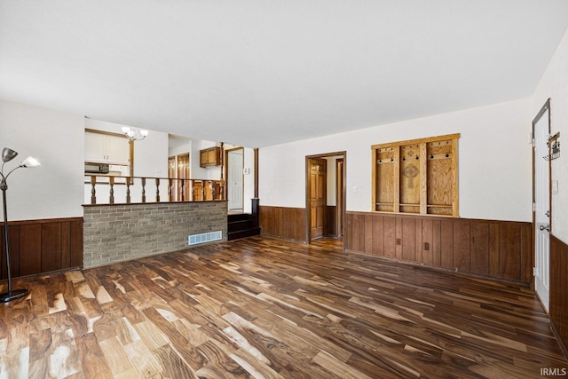 interior space with wood-type flooring, wooden walls, and a chandelier