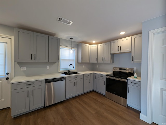 kitchen featuring appliances with stainless steel finishes, sink, gray cabinetry, and decorative light fixtures