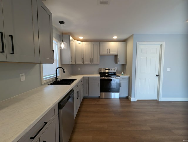 kitchen featuring sink, dark wood-type flooring, appliances with stainless steel finishes, gray cabinetry, and decorative light fixtures