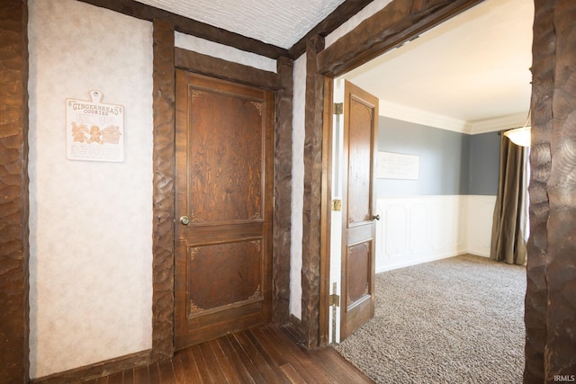 corridor with ornamental molding and dark hardwood / wood-style floors