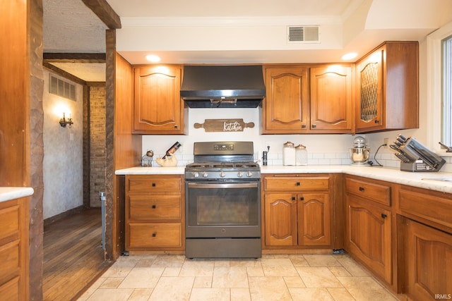 kitchen with crown molding, stainless steel range with gas stovetop, and wall chimney exhaust hood